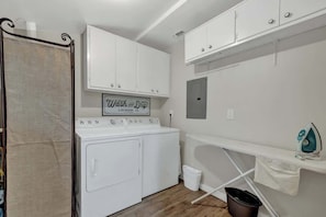 Un espace dédié à la buanderie, équipé d’une machine à laver, d’un étendoir et d’une enseigne indiquant « Wash and Dry Laundry Co. ».