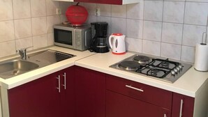 A compact kitchen with a gas stove, microwave, and coffee maker. - Cosy Apartment Near the Beach in Medulin, Croatia (Medulin)