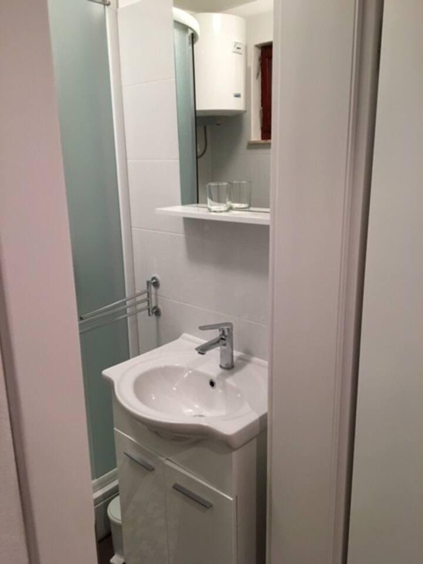A small bathroom with a white sink, a mirror, and a cabinet above it.