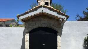 A stone-built outdoor kitchen with a black door, a stone countertop, and a small chimney. - Cosy Apartment Near the Beach in Medulin, Croatia (Medulin)