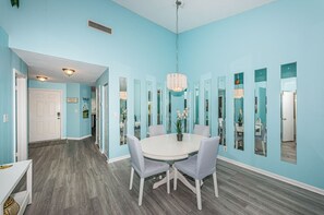 A dining area with a round table, chairs, and a chandelier.