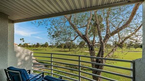 Un espacio de estar al aire libre cubierto, con vista a un campo de golf.