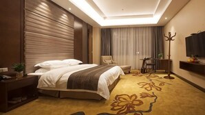 Una habitación de hotel con cama, mesita de noche, lámpara, sillón y televisor.