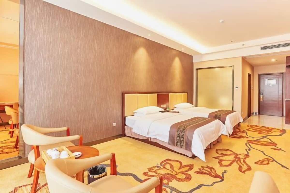 A hotel room with two beds, a dining area with chairs, and a large mirror.