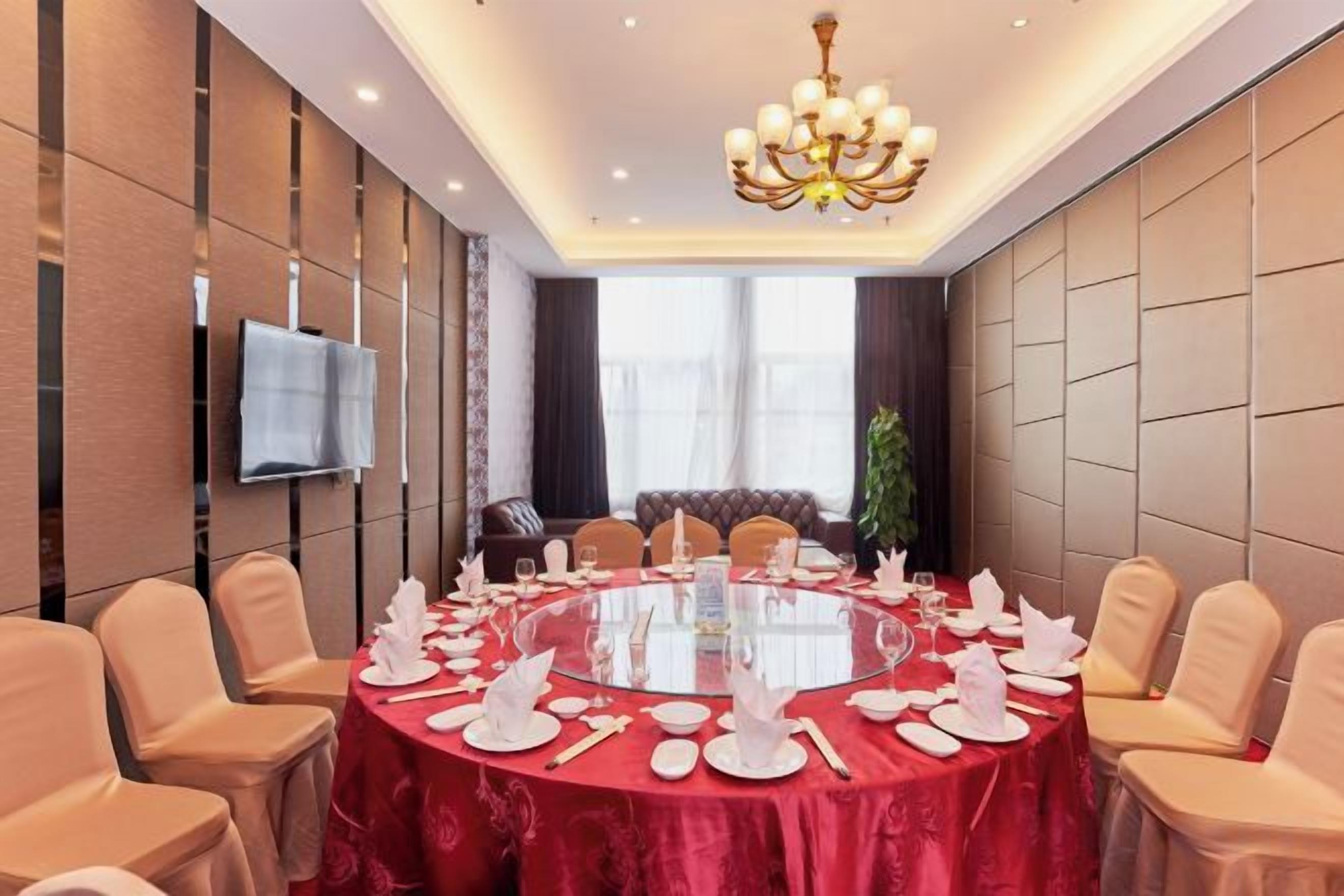 A conference room with a round table, chairs, and a TV mounted on the wall.