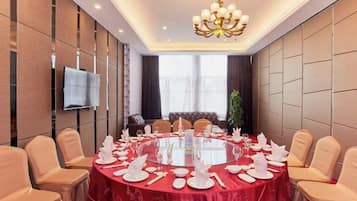 A conference room with a round table, chairs, and a TV mounted on the wall.