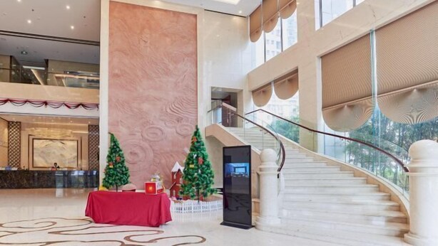 Un amplio vestíbulo con una columna de mármol, una escalera y decoración navideña.
