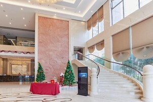 Un amplio vestíbulo con una columna de mármol, una escalera y decoración navideña.