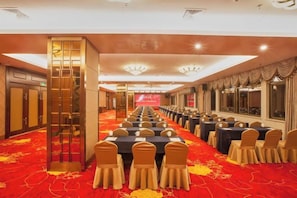 A banquet hall with long tables and chairs, a red carpet, and a large screen at the front. - Shanhai Hotel (Longyan)