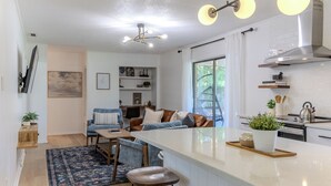 Une cuisine moderne dotée d’un îlot central, un coin repas avec un canapé et des chaises, et un salon avec une grande fenêtre.
