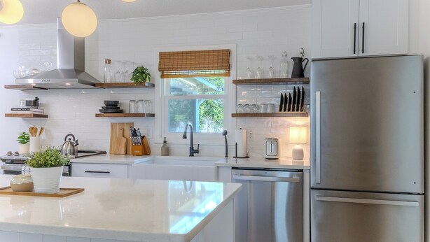 Une cuisine moderne avec des meubles blancs, des appareils en acier inoxydable et un îlot central.