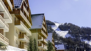 A multi-story hotel with balconies, a snowy mountain backdrop, and a clear sky. - 100m from ski slopes, Ground floor, balcony, 29m², Valloire (Valloire)