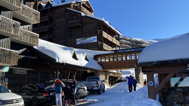 Un edificio in legno con balconi e un'indicazione che segnala un luogo per praticare surf.