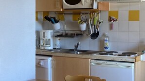 Una cucina compatta con mobili in legno, un forno a microonde, una macchina del caffè e un lavandino.