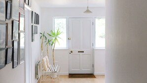 A hallway with a white door, a bench, and a potted plant. - Secluded rural retreat, close to beach - sleeps 12 (West Sussex)