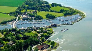 An aerial view of a marina with boats docked, surrounded by green fields and residential buildings. - Goodwood Revival 6 Bed Retreat, Secure Parking (Birdham)