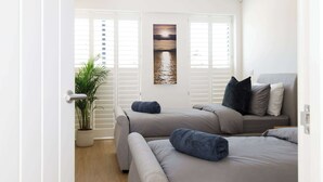 A modern living room with a sofa set, a potted plant, and a painting on the wall. - Luxury designer coastal home for 10 with hot tub (West Wittering)