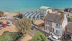 Une ville côtière dotée d’une plage, de voitures garées et d’immeubles présentant un mélange de styles architecturaux.