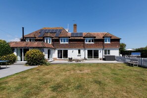 A two-story house with solar panels, a chimney, and a fenced backyard. - Beach house with pool in West Wittering (West Wittering)