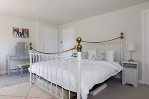 A white four-poster bed with a gold frame, a bedside table, a nightstand, a lamp, and a picture on the wall. - Beach house with pool in West Wittering (West Wittering)