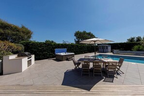 A poolside area with a hot tub, outdoor seating, and a small shed. - Beach house with pool in West Wittering (West Wittering)