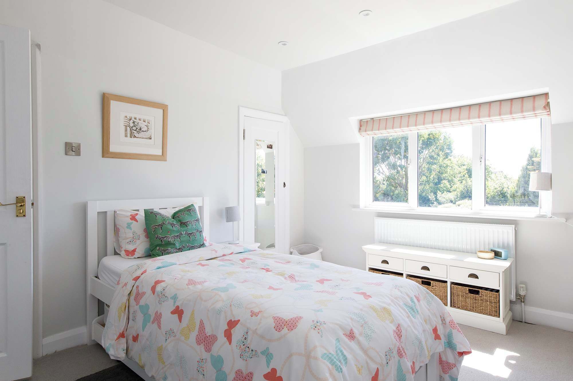 Un dormitorio con cama, ventana con persianas, mesita de noche y radiador.