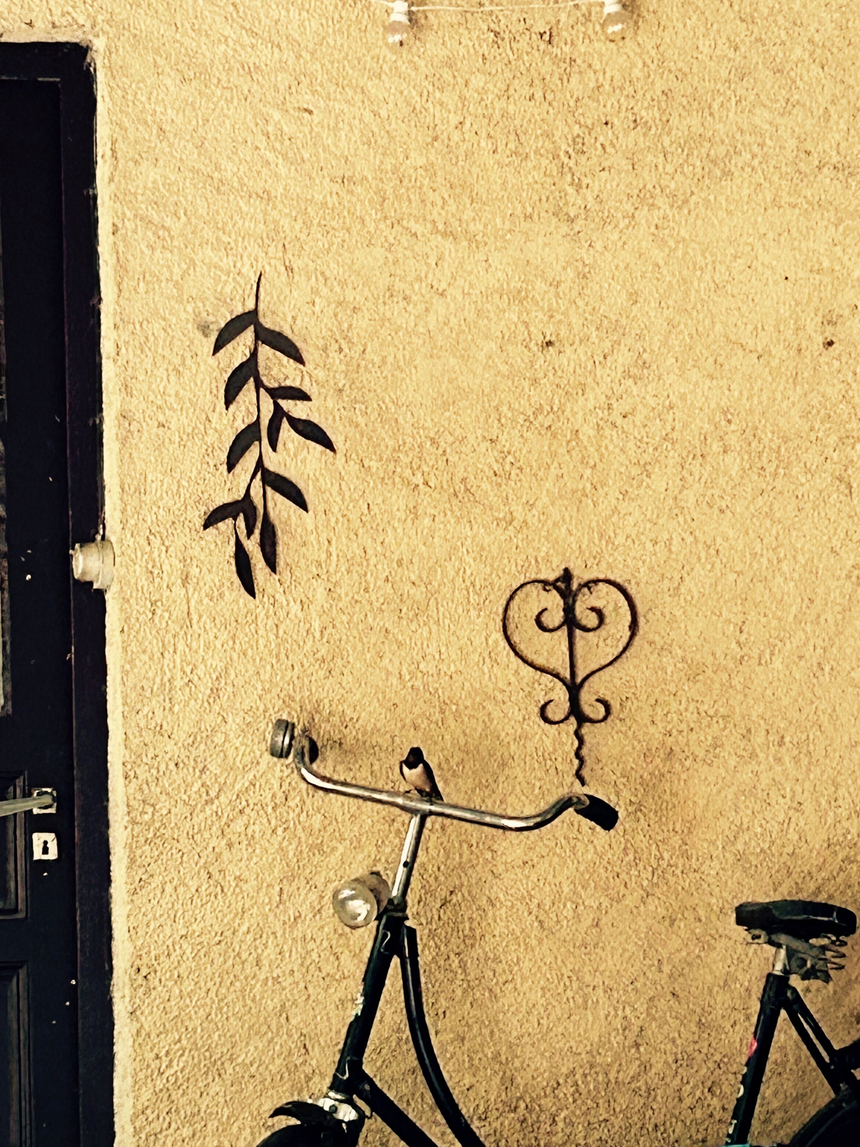 Una bicicleta apoyada en una pared texturizada con diseños metálicos decorativos.