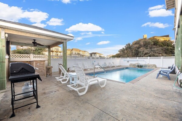 Relax by the pool surrounded by a patio and barbecue grill.