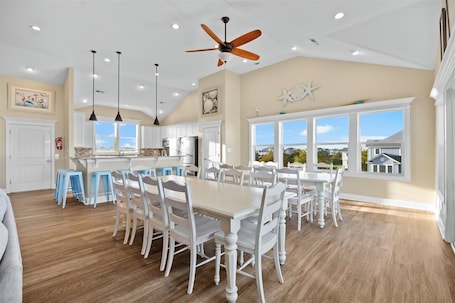A spacious kitchen with white cabinetry, a large island, and a dining area with white chairs.
