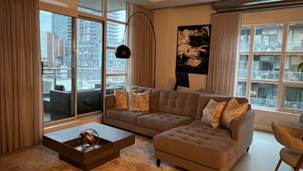 Ein modernes Wohnzimmer mit einer Eckcouch, einem Couchtisch und einem großen Fenster mit Blick auf die Stadt.