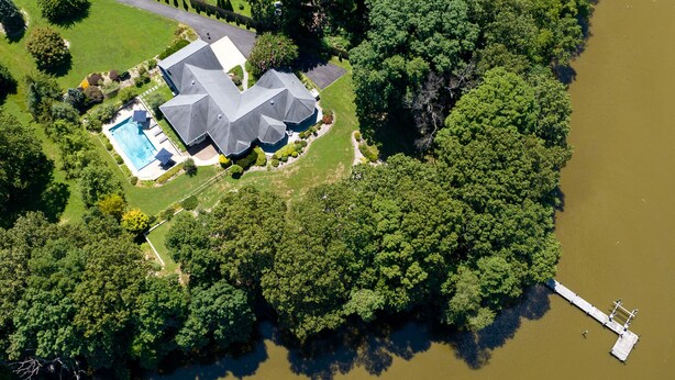 Vista aérea de una casa con piscina, rodeada de abundante vegetación y una masa de agua.