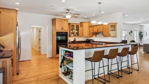 Una cocina amplia con armarios de madera, una isla central con taburetes altos y un ventilador de techo.