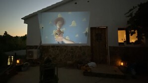 En byggnad med en stor utomhusduk där en film visas.