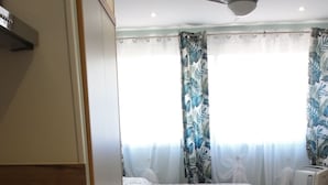 A compact kitchen with a refrigerator, stove, and a small dining table with a chair. - Comfort studio - Double bed + single bed - FAME MARINA BAIE DES ANGES (Villeneuve-Loubet)