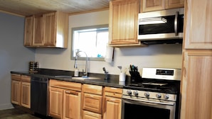 A kitchen with wooden cabinets, a stainless steel dishwasher, a microwave, and a stove. - Mill town location by the river w/hot tub (Bonner-West Riverside)