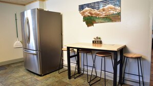 A kitchen with a stainless steel refrigerator, a wooden table with stools, and a painting on the wall. - Mill town location by the river w/hot tub (Bonner-West Riverside)