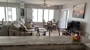 A spacious living room with a marble coffee table, a sofa set, and a dining area with chairs.