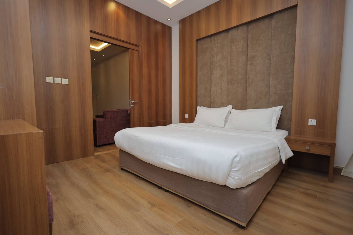 Une chambre moderne avec un grand lit, des murs en bois et une tête de lit intégrée.