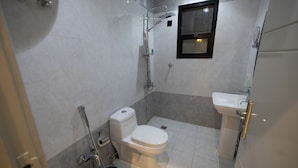 A small, modern bathroom with a toilet, shower, and sink. - Malath Raqi (Riyadh)