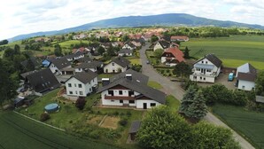 Vista aérea de una zona residencial con casas, campos verdes y una montaña al fondo.