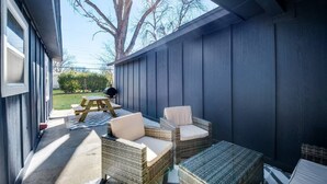 A covered patio with wicker furniture and a picnic table.