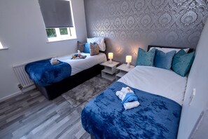 Une chambre avec deux lits, un papier peint à motifs et des lampes de chevet.
