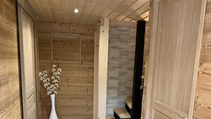 A wooden interior hallway with a tiled floor, a white vase with flowers, and a staircase.