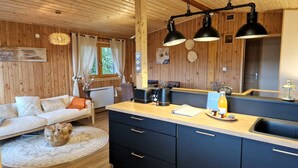 A cozy cabin interior with a wooden interior, a sofa, a dining table, and a kitchen area.