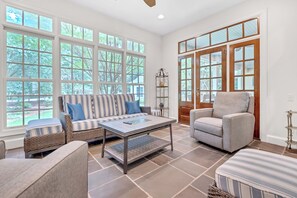 A spacious living room with a large window, a sofa, a chair, and a coffee table. - Heart of Historic Pinehurst, Golf, Saltwater Pool (Pinehurst)