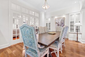 A dining room with a large wooden table, ornate chairs, and a chandelier.