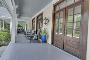 A covered porch with a row of chairs and a large potted plant. - Heart of Historic Pinehurst, Golf, Saltwater Pool (Pinehurst)