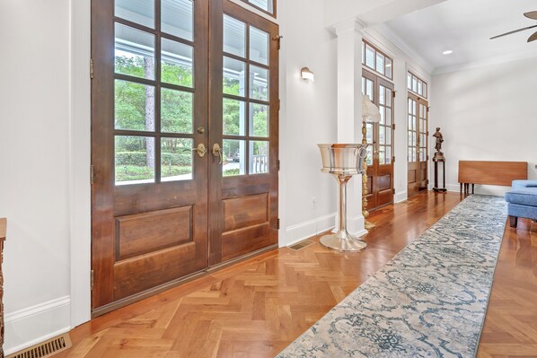 A hallway with wooden flooring, large double doors, and a blue patterned rug. - Heart of Historic Pinehurst, Golf, Saltwater Pool (Pinehurst)