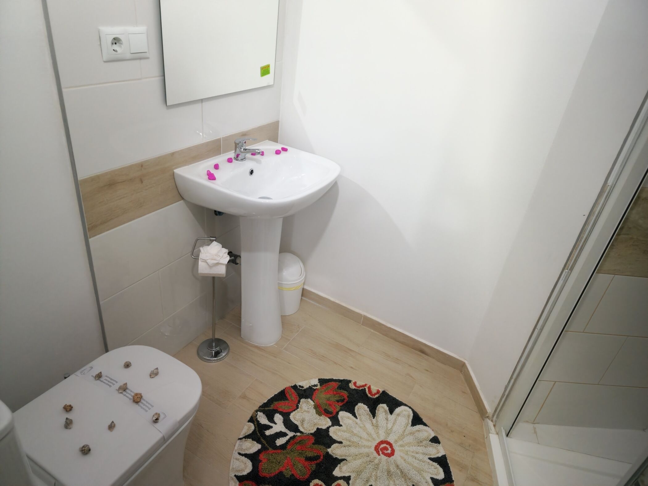 A bathroom with a white sink, toilet, and a small rug on the floor.