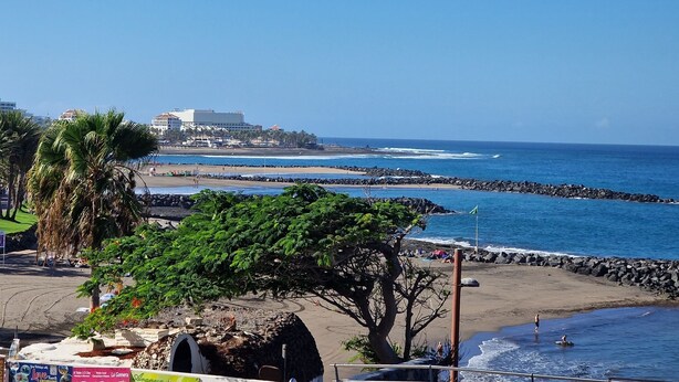 A coastal hotel with a view of the ocean, a beach, and a rocky shoreline. - 301, 2 bedrooms,close Playa las Americas&free wifi (Playa de la Américas)